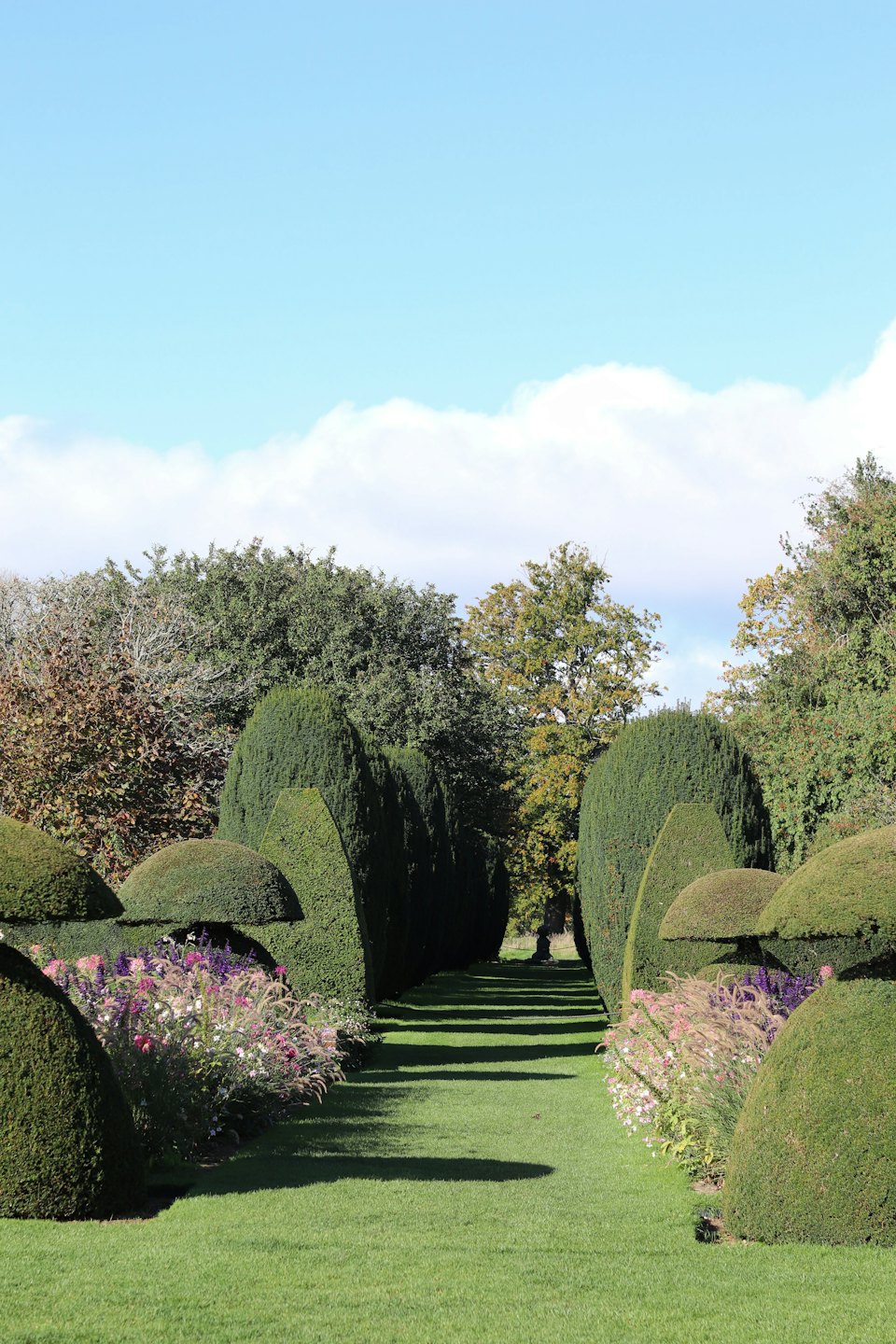 Ein gepflegter Gartenweg schlängelt sich durch hohe Hecken und Blumen.